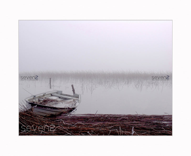 extremely tranquil and peaceful scene of rowing boat on a misty lake with reeds