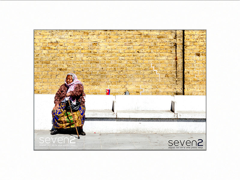 old woman with walking stick dresssed in ethnic clothing sitting on stone bench in London